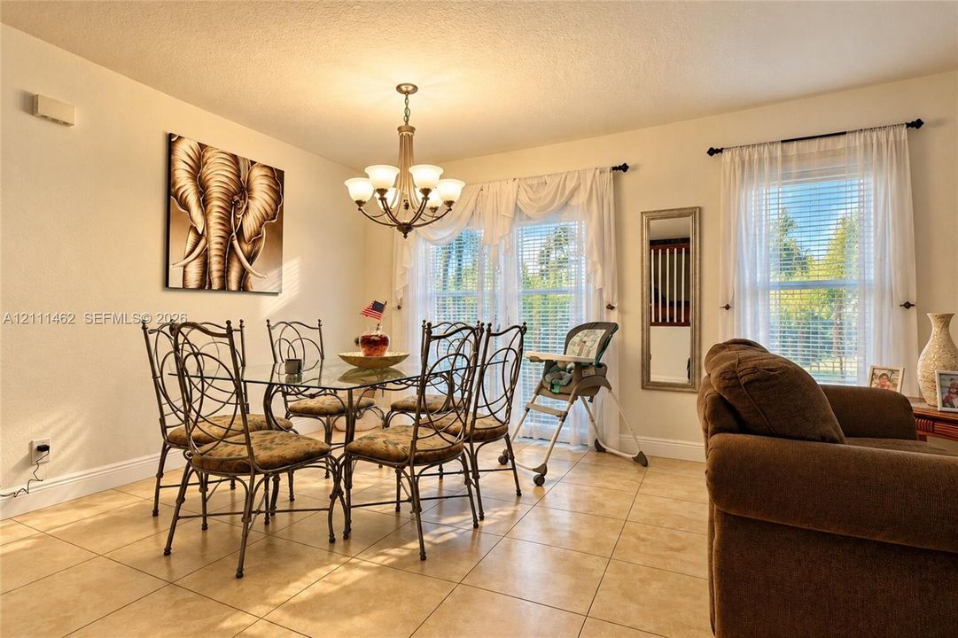 Ceramic tile flooring, classic multi-arm chandelier, and dual windows with horizontal blinds