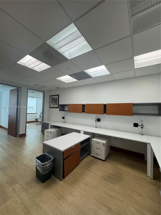 Drop ceiling with recessed lighting, wood-finish flooring, and extensive built-in cabinetry featuring white work surfaces and integrated storage drawers