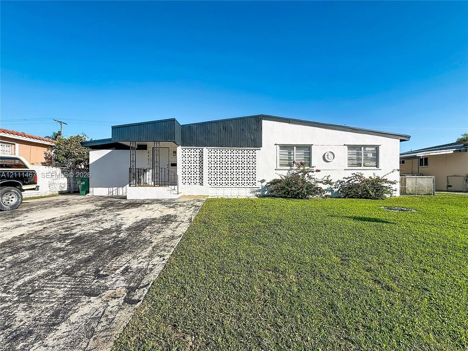 Mid-century modern exterior featuring a low-slope roofline, decorative breeze block screening, contrasting dark trim, and a concrete driveway