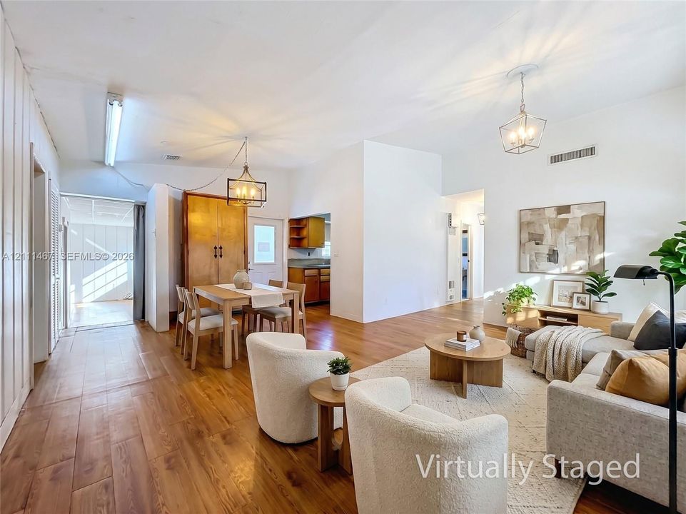 Open-concept interior featuring wood-finish flooring, high ceilings, dual hanging lantern-style light fixtures, and built-in cabinetry