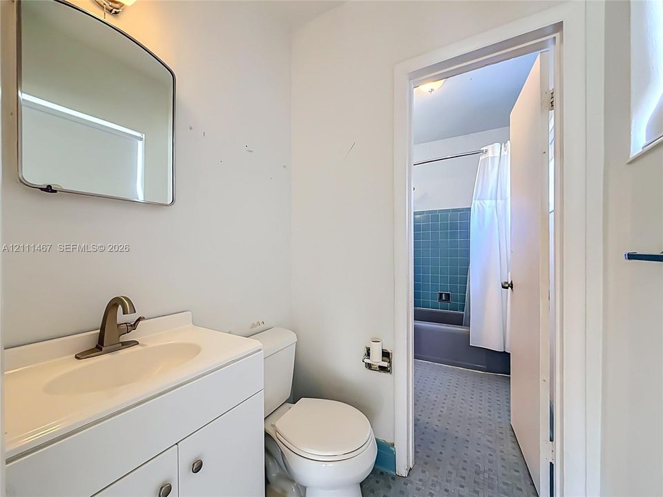 Bathroom featuring a white vanity with an integrated sink, brushed metal faucet, wall-mounted mirror, and a tiled shower enclosure