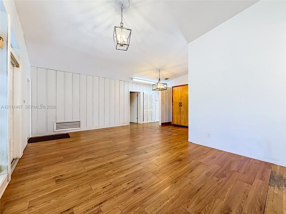 Vaulted ceilings featuring decorative board and batten wall paneling, wood-finish flooring, and dual geometric pendant light fixtures