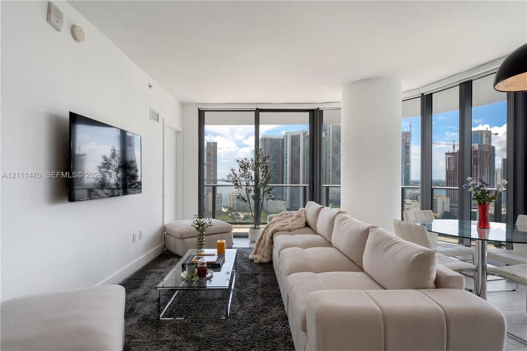 Floor-to-ceiling windows, high-rise urban skyline scenery, and neutral ceramic tile flooring