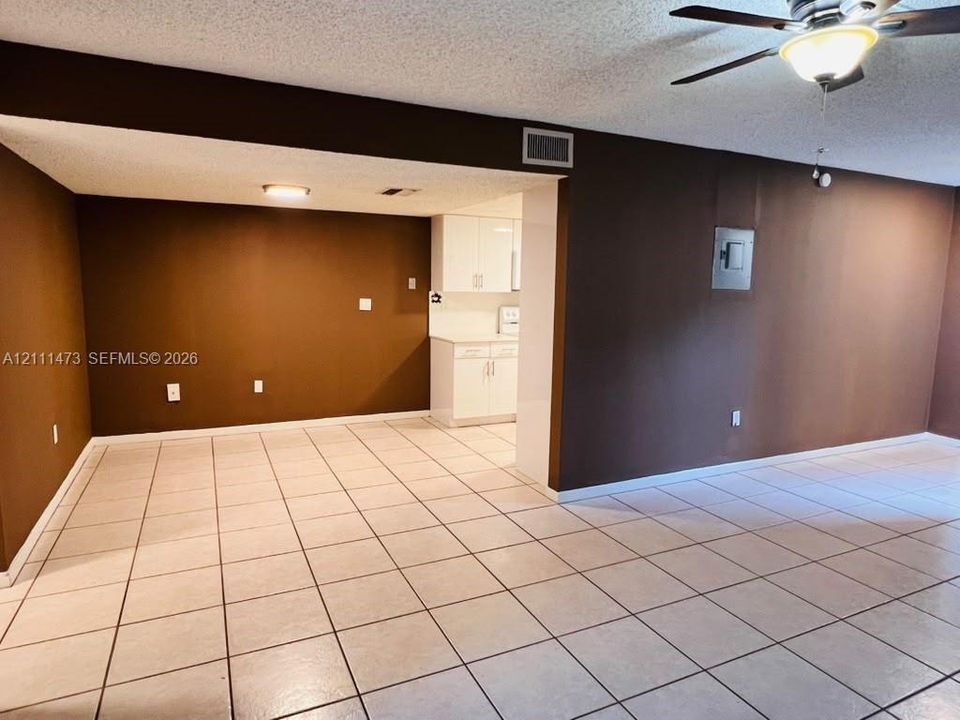 Ceramic tile flooring, white cabinetry, ceiling fan with integrated light fixture, and textured ceilings