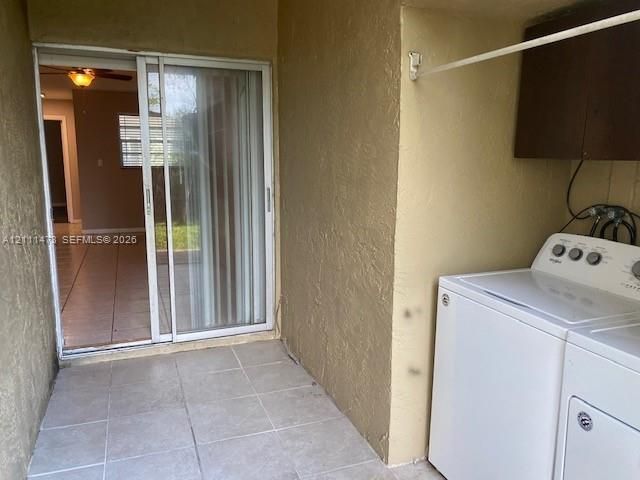 Covered outdoor utility area featuring ceramic tile flooring, sliding glass door entry, and wall-mounted cabinetry