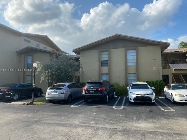 Multi-story exterior featuring a textured stucco finish, low-pitched rooflines, and assigned asphalt parking