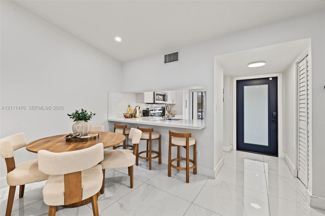 Polished tile flooring, breakfast bar with a solid surface countertop, and an exterior door featuring a frosted glass panel