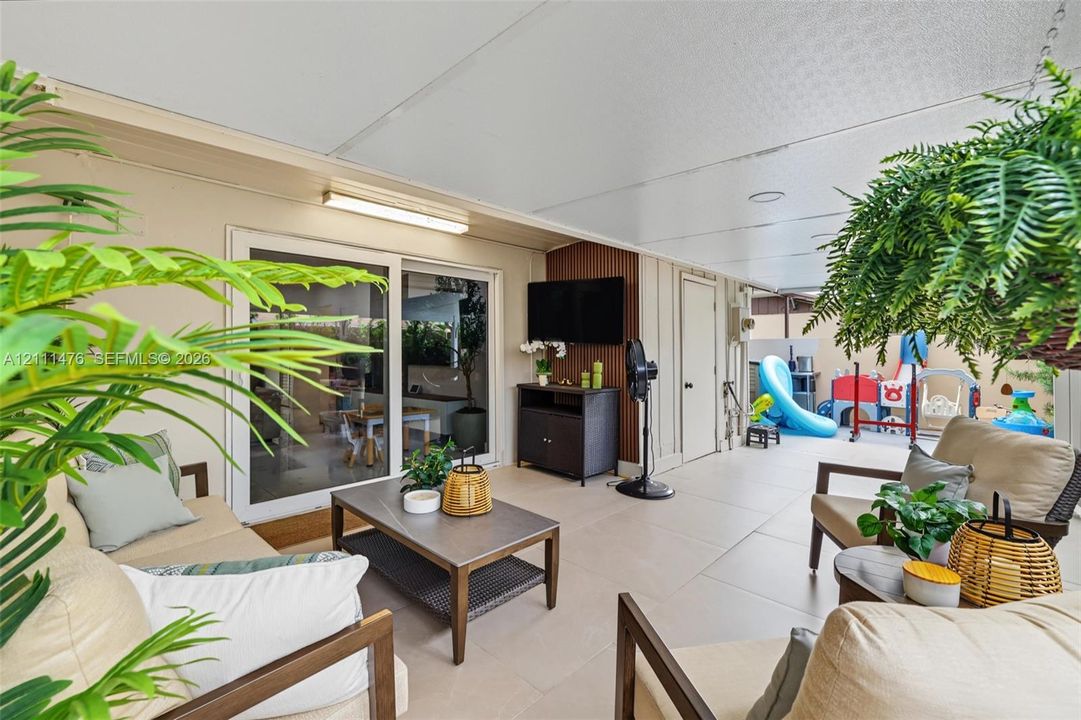 Covered patio featuring large-format tile flooring, recessed ceiling lighting, and sliding glass door access