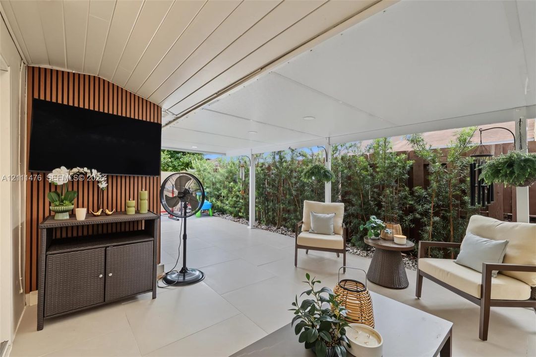Covered patio featuring large-format tile flooring, a vertical slat wood-finish accent wall, and recessed ceiling lighting