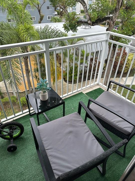 Balcony featuring white metal railing and outdoor turf flooring