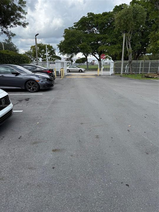 Asphalt parking area featuring marked parking spaces, a metal perimeter fence, and a gated entrance