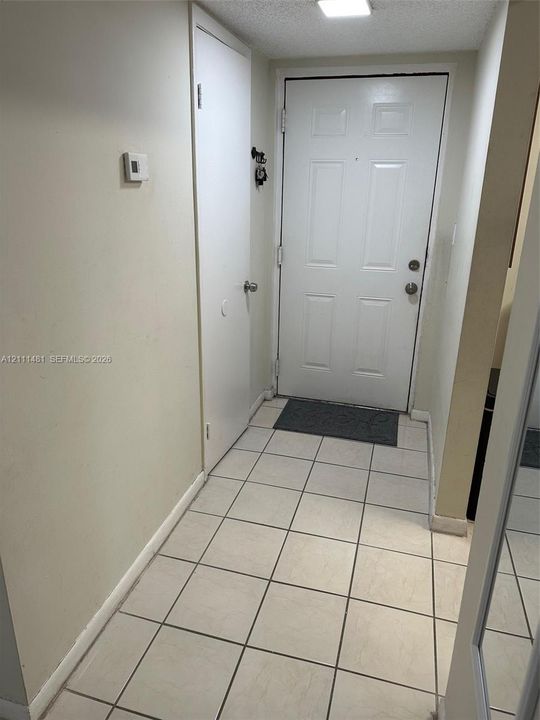 Entryway featuring square ceramic tile flooring, a six-panel door with metal hardware, and a closet with a solid-core door