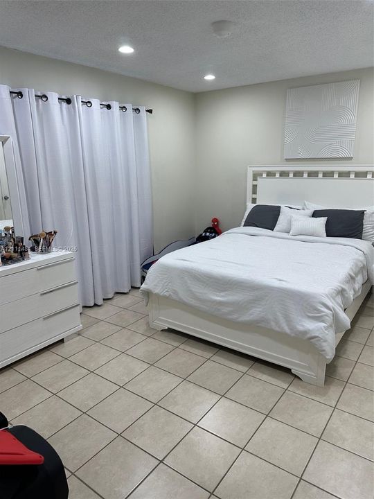Neutral-toned ceramic tile flooring, recessed ceiling lighting, and floor-to-ceiling curtain panels