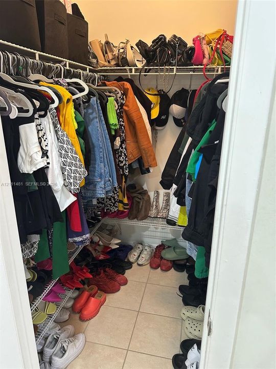 Walk-in storage space featuring multi-tiered wire shelving and ceramic tile flooring