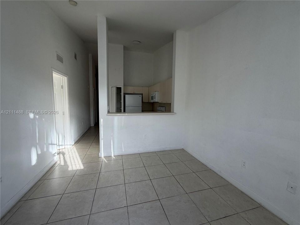Open-concept floor plan featuring tile flooring, neutral wall tones, and a pass-through kitchen opening