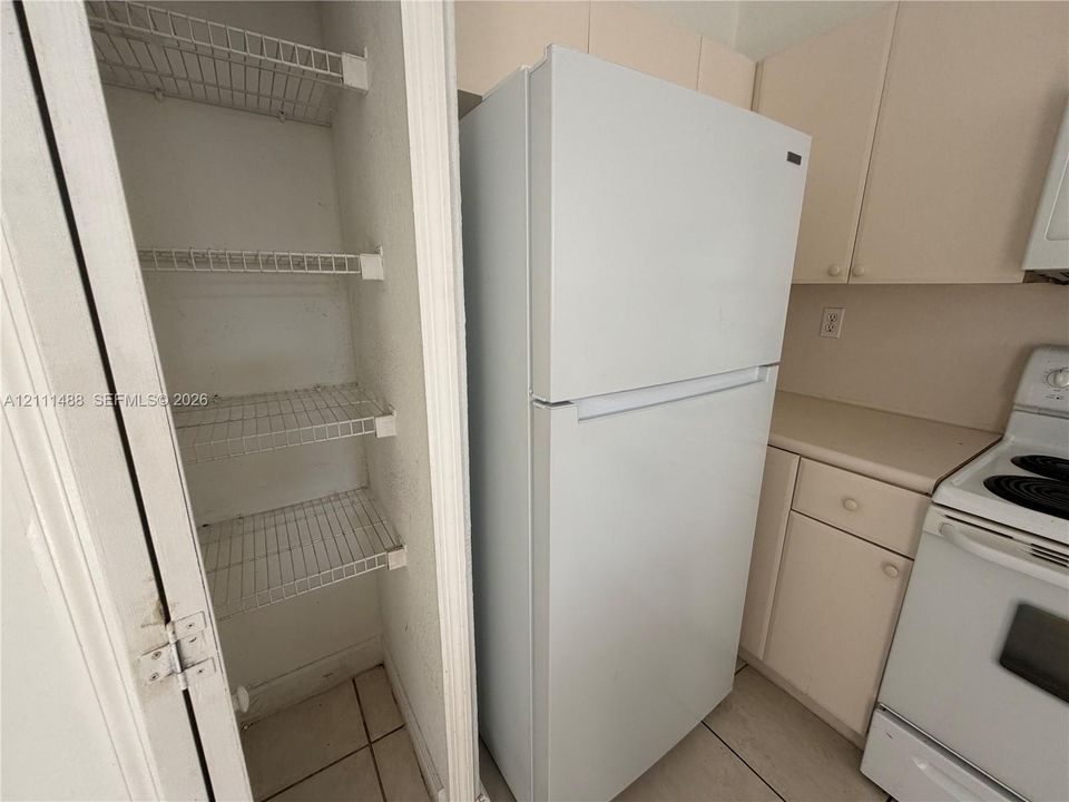 Kitchen featuring white cabinetry, integrated white appliances, solid surface countertops, and a built-in pantry with wire shelving