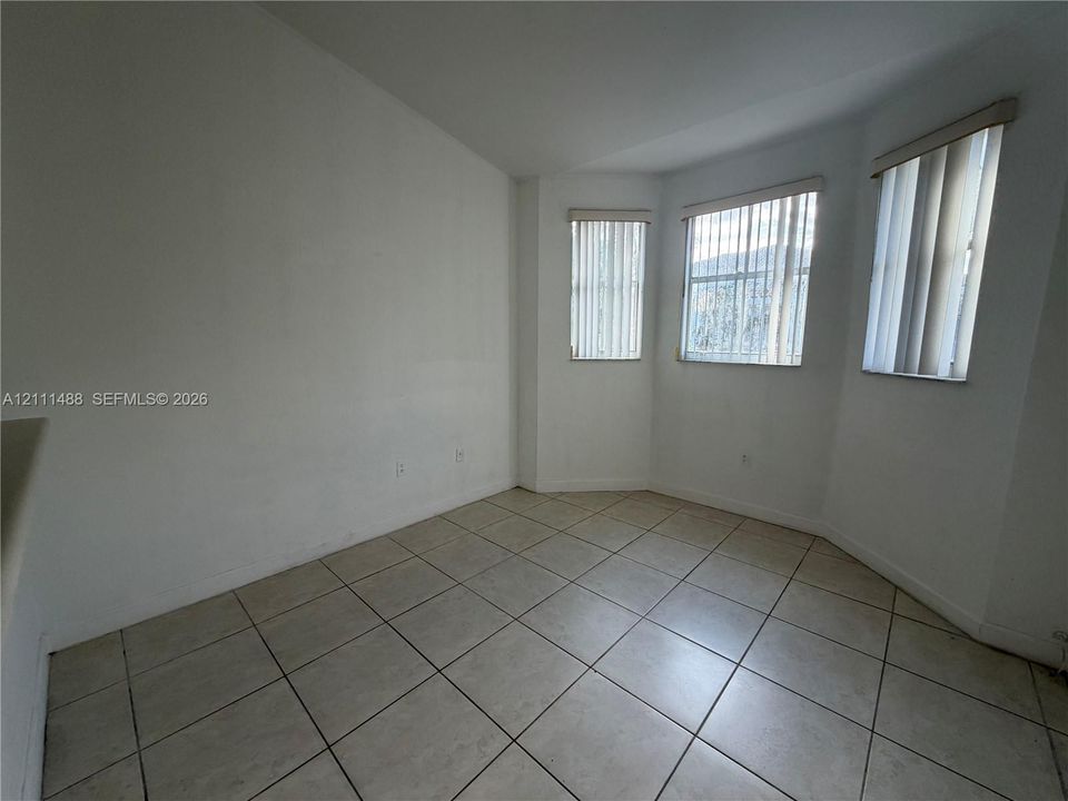 Interior room featuring large-format ceramic tile flooring, neutral walls, and a multi-window bay configuration with vertical blinds