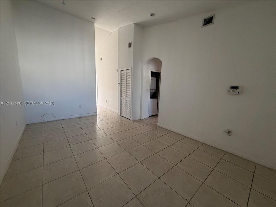 High-ceiling interior featuring neutral tile flooring, an arched doorway, and built-in louvered closet doors