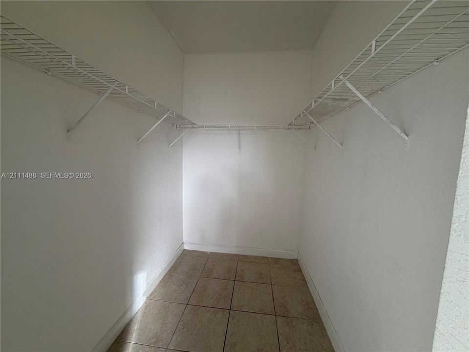 Walk-in storage space featuring ceramic tile flooring and white wire shelving