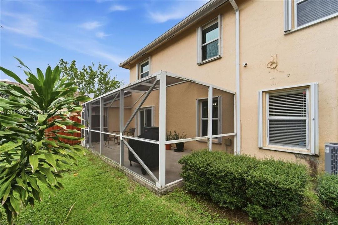 Stucco exterior featuring a screened-in lanai with a concrete floor and aluminum framing