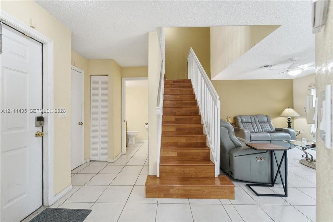 Foyer featuring tile flooring, staircase with wood-finish treads, and white vertical balusters