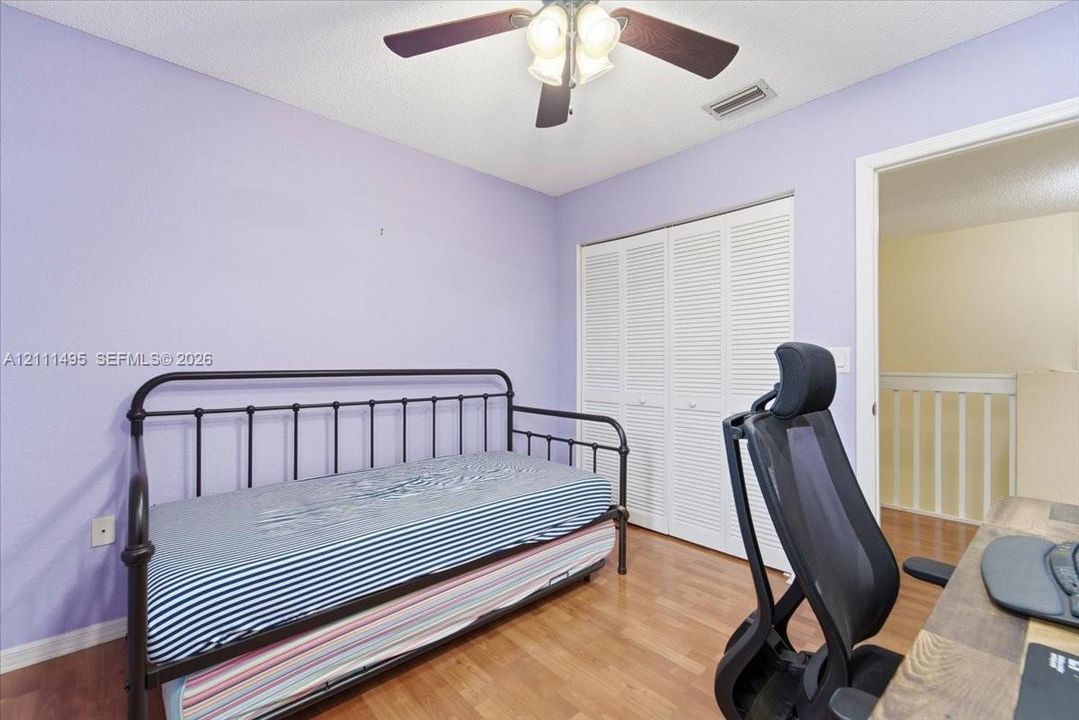 Room featuring wood-finish flooring, a ceiling fan with integrated lighting, and a closet with bifold louvered doors