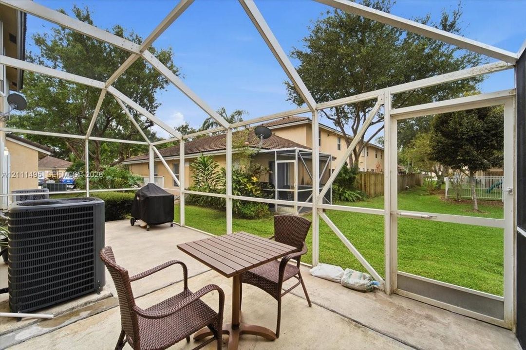 Screened-in concrete patio enclosure with a glass-paneled entry door and a manicured backyard
