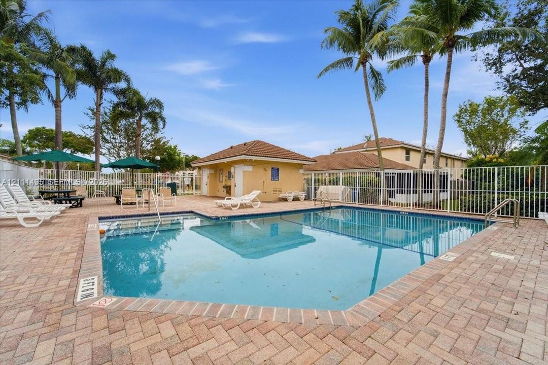 Swimming pool with a brick-paver deck, cabana, and perimeter fencing