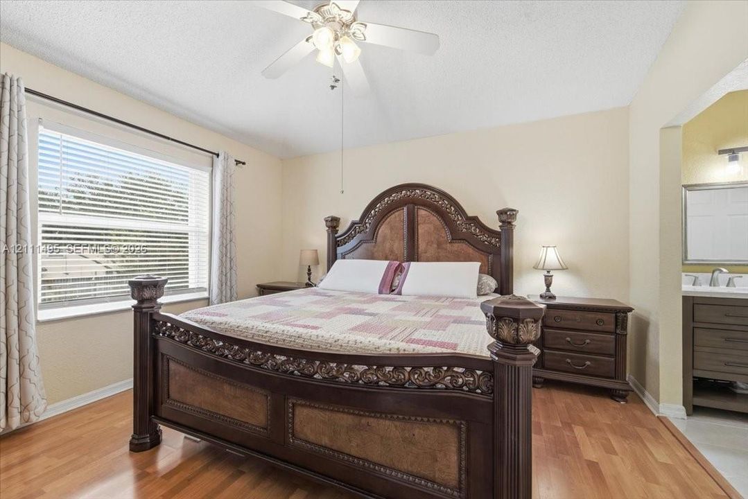 Room featuring wood-finish flooring, a multi-blade ceiling fan with integrated lighting, and a window with horizontal blinds