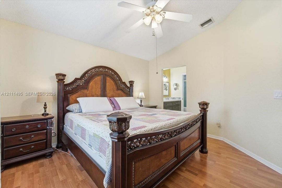 Vaulted ceiling with a central multi-blade ceiling fan and wood-finish flooring