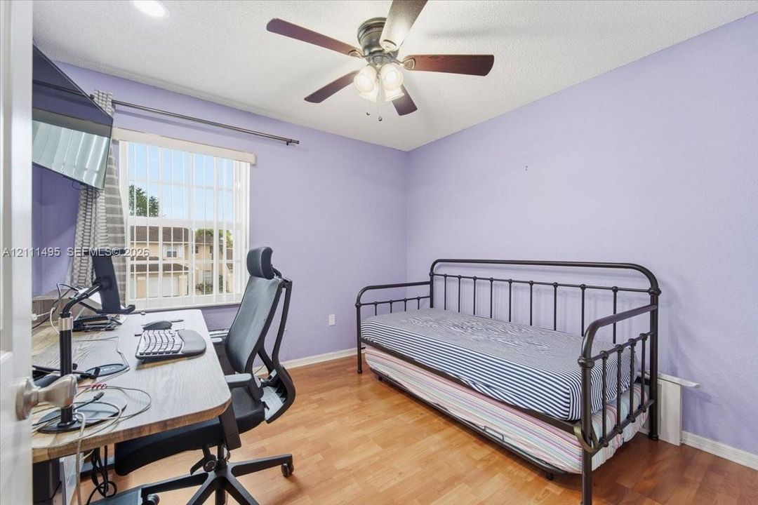 Room featuring wood-finish flooring, a ceiling fan with integrated lighting, and a window with horizontal blinds