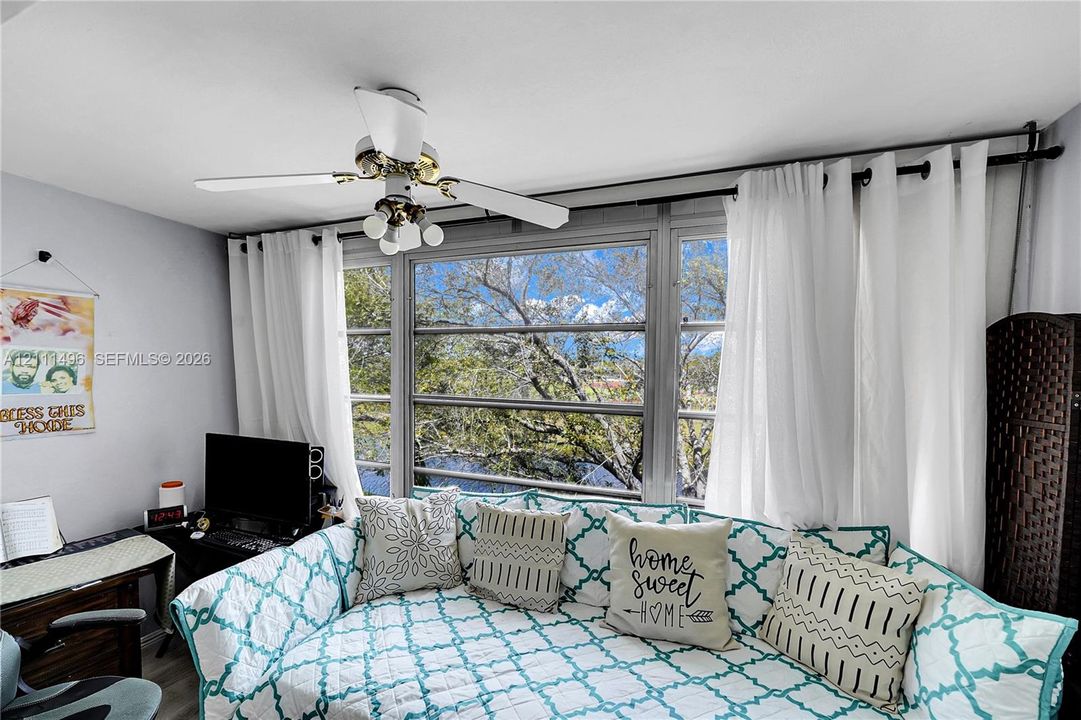 Large multi-pane window with metal frame and white ceiling fan with integrated lighting