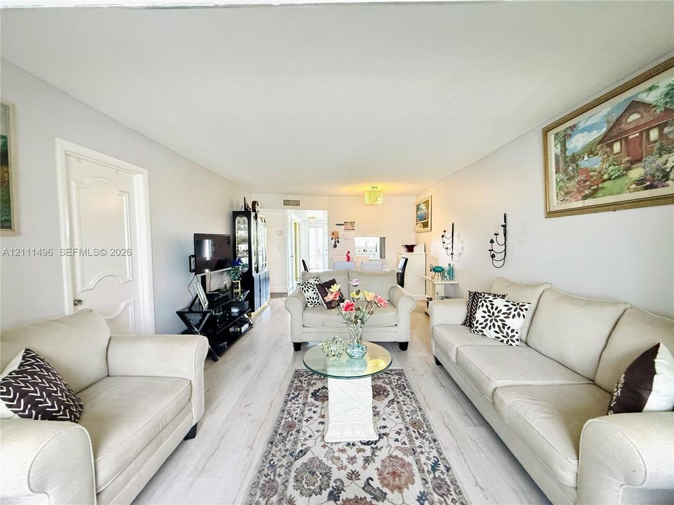 Living area featuring light-toned wood-finish flooring, smooth ceilings, and arched-panel interior doors