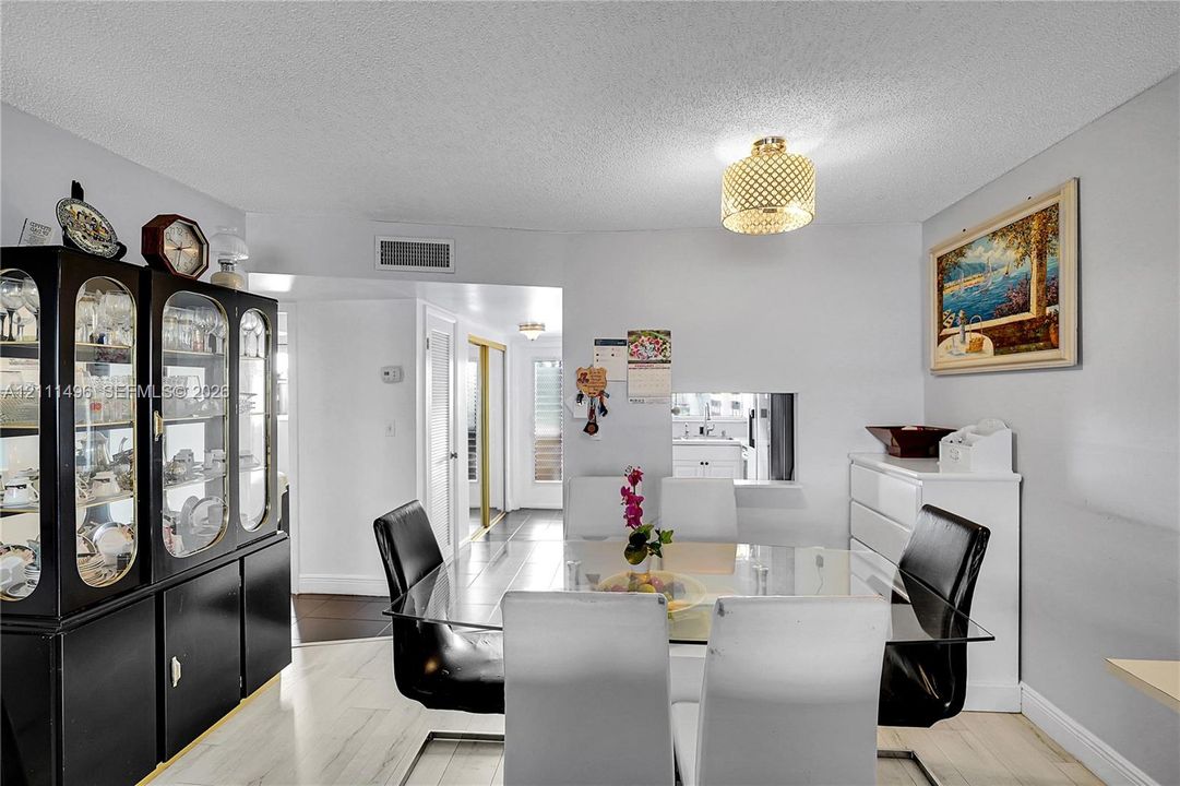 Interior space featuring light-toned flooring, recessed ceiling lighting, and a pass-through window to the kitchen