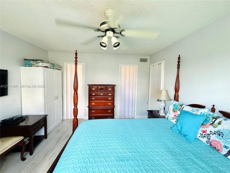 Neutral-toned walls, wood-finish flooring, and a ceiling fan with integrated light fixture