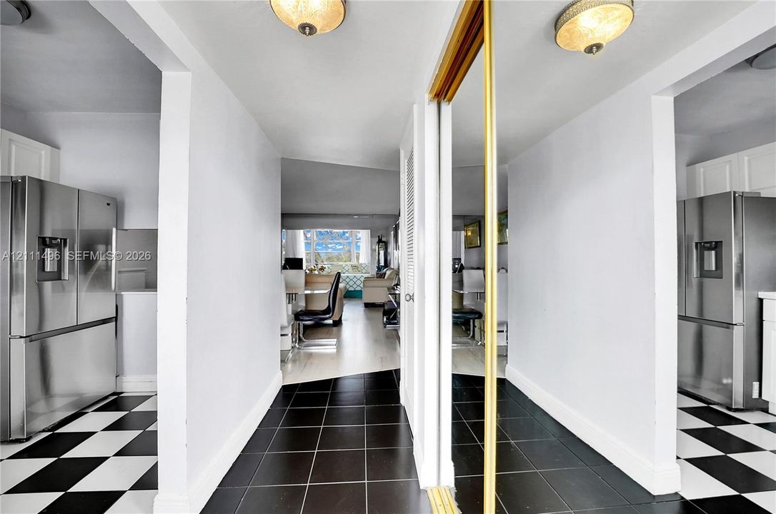 Hallway featuring black tile flooring, a mirrored sliding closet door, and two ceiling-mounted dome light fixtures