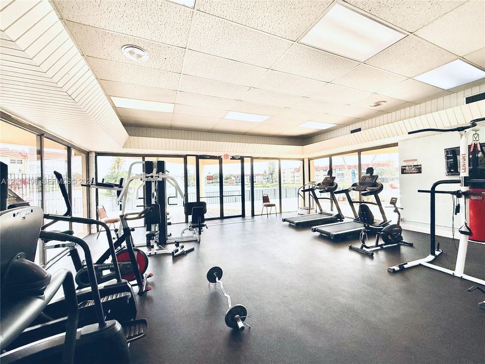 Fitness room featuring floor-to-ceiling glass walls, rubberized flooring, and inset panel lighting
