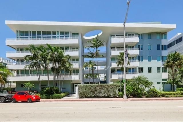 Contemporary multi-story exterior featuring a prominent circular architectural cutout, expansive balconies with glass railings, and mature palm tree landscaping