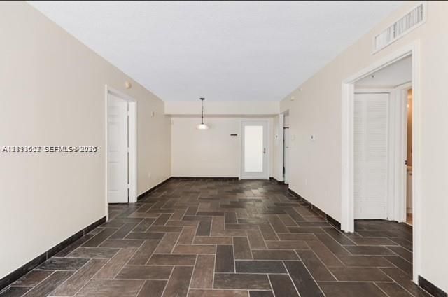 Interior space featuring dark wood-finish flooring in a herringbone pattern, neutral wall tones, a recessed ceiling light fixture, and a glass-paneled exterior door