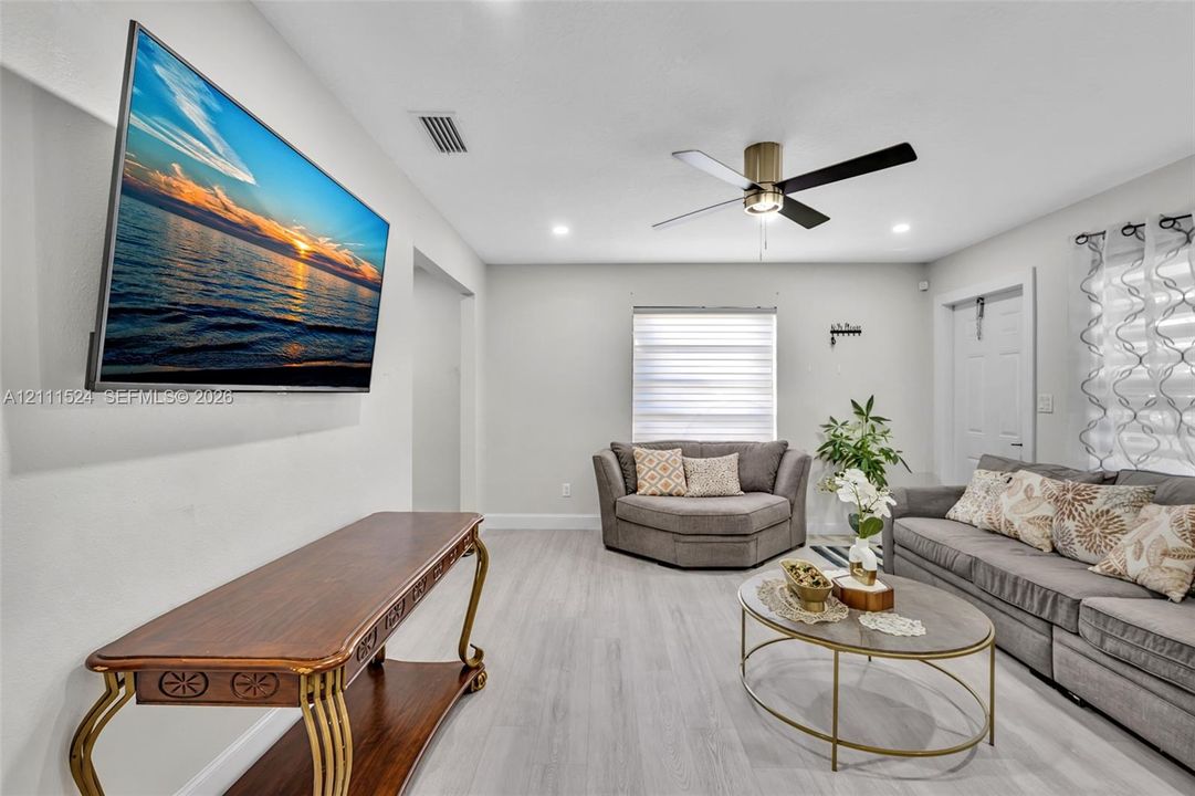 Living area featuring light-toned wood-finish flooring, recessed lighting, and a modern ceiling fan with a metallic finish