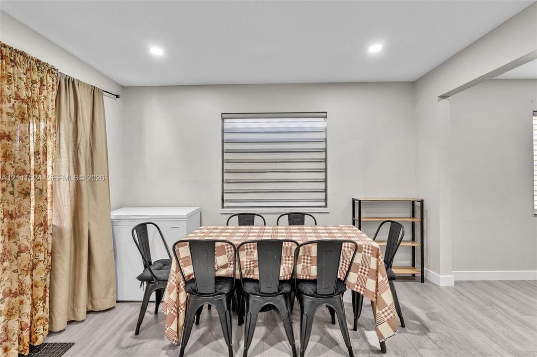 Neutral walls, recessed lighting, wood-finish flooring, and a window featuring banded roller shades