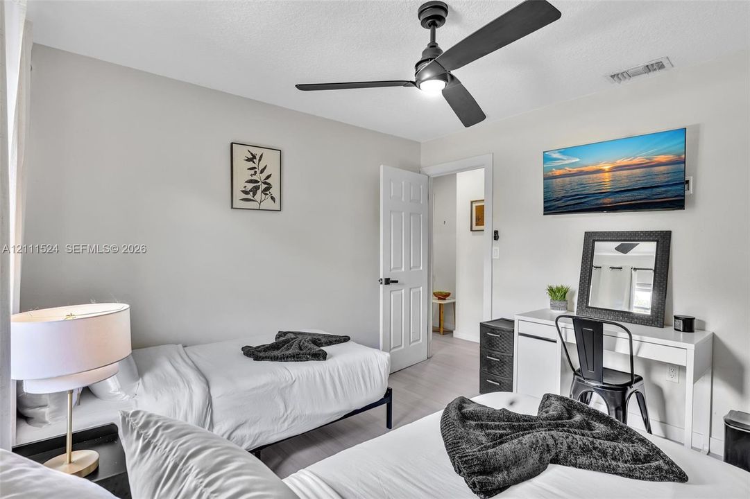 Neutral-toned room featuring a matte black ceiling fan with integrated lighting and a white six-panel interior door