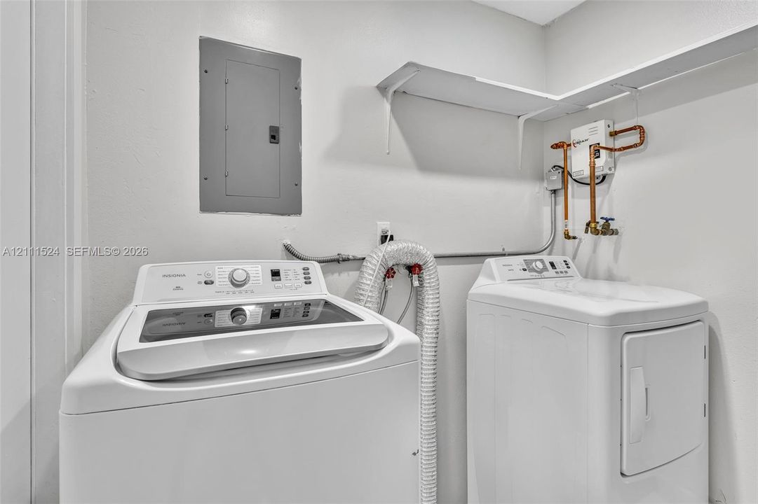 Utility area featuring wall-mounted shelving, an electrical panel, and dedicated laundry hookups