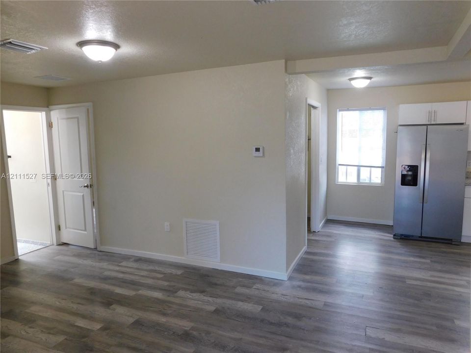 Wood-finish flooring throughout, stainless steel side-by-side refrigerator, flush-mount ceiling lighting, and solid-core interior doors