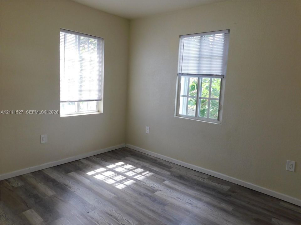 Neutral interior featuring wood-finish flooring and two multi-pane windows with integrated blinds