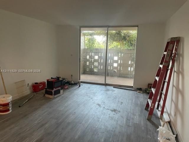 Interior space featuring wood-finish flooring, floor-to-ceiling sliding glass doors, and a private patio enclosed by decorative concrete block screening