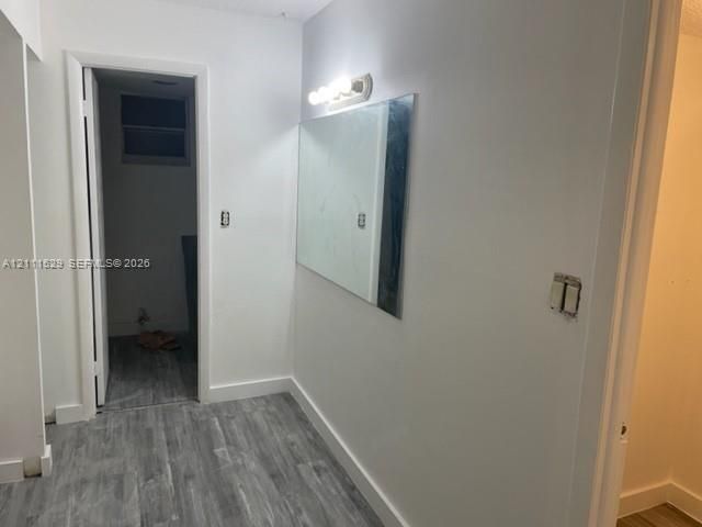 Neutral-toned wood-finish flooring, wall-mounted vanity mirror, and four-bulb vanity lighting fixture