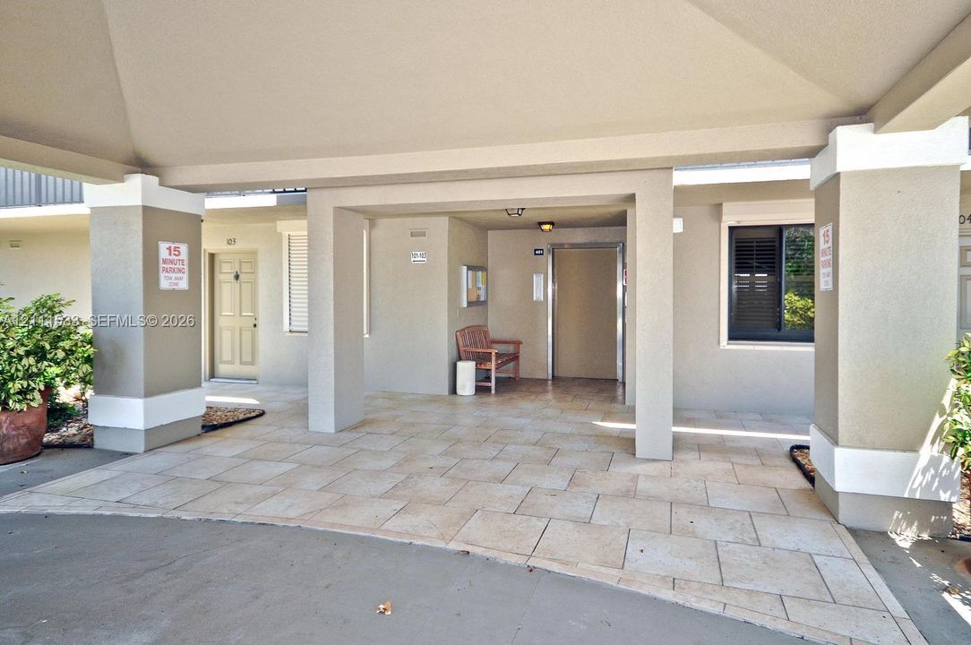 Covered entryway featuring a stone-tiled floor, structural columns with molded detailing, and recessed exterior lighting