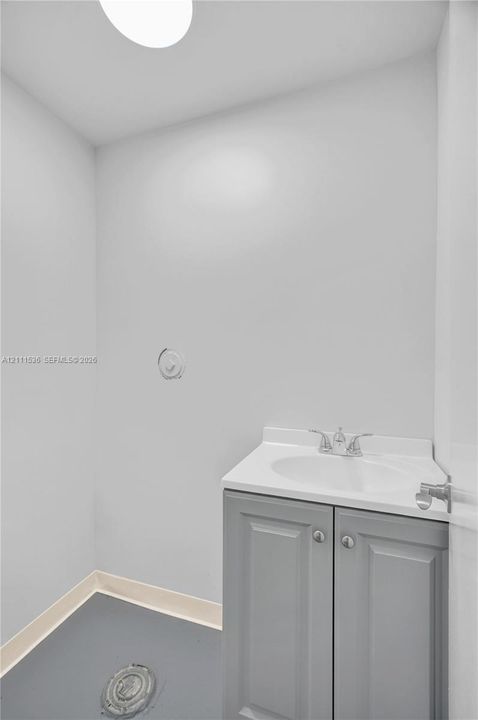 Vanity cabinet with shaker-style doors, integrated sink, dual-handle chrome faucet, and ceiling-mounted light fixture