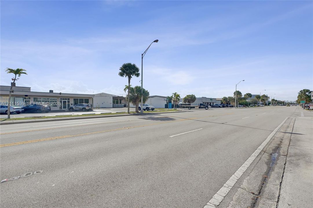 Multi-tenant commercial property exterior featuring paved surface parking and mature palm trees situated along a public roadway